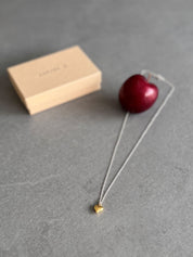 Necklace with a gold heart pendant on next to a personalised gift box.