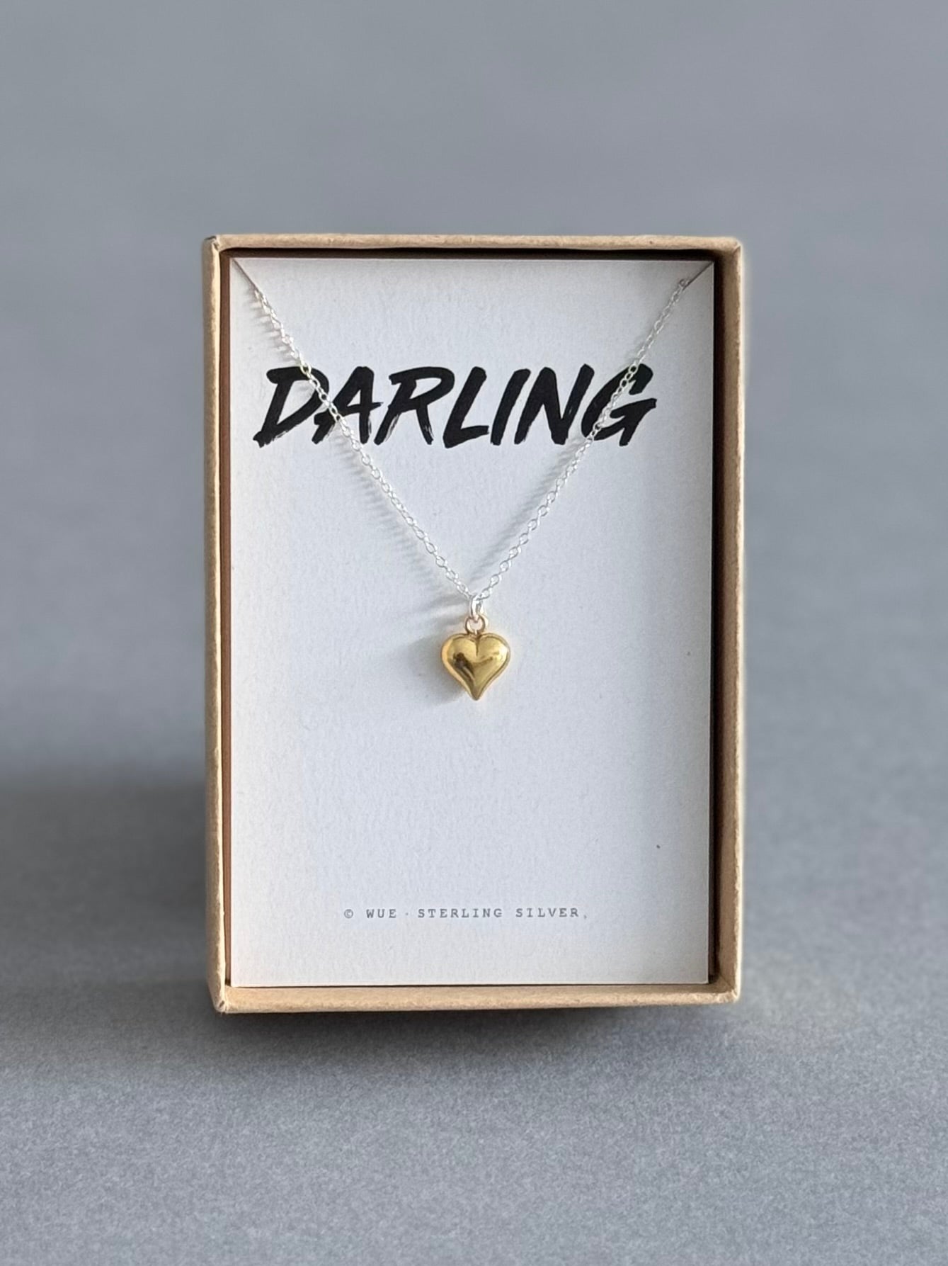 Gold heart necklace on a card with 'Darling' in a gift box.