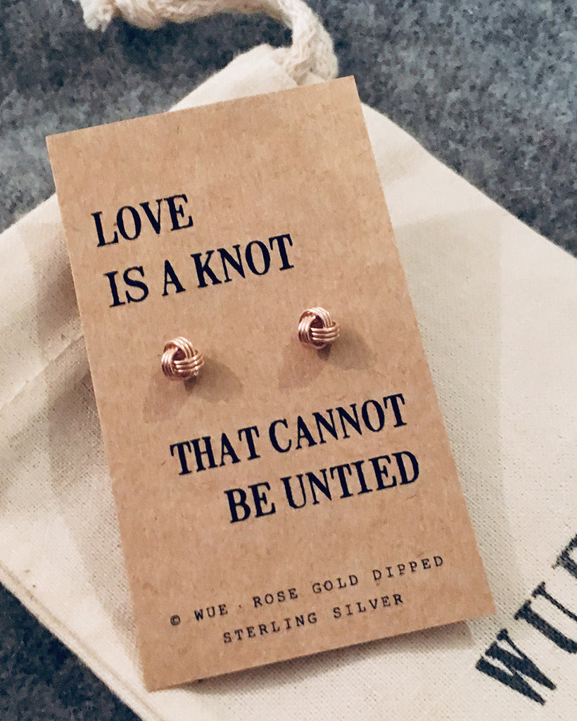 Rose gold earrings on a 'Love is a knot' card with WUE branding.