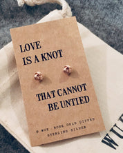 Rose gold earrings on a 'Love is a knot' card with WUE branding.