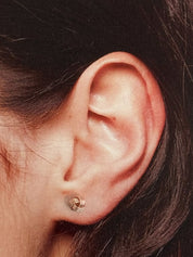 Close-up of an ear wearing a small rose gold knot earring 